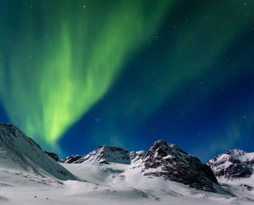 Ervaar de sensatie van avontuur onder het majestueuze groene noorderlicht dat de besneeuwde toppen van Kebnekaise, Zweden, verlicht.