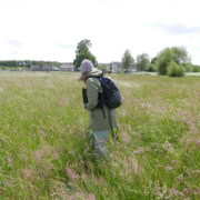 Kaart en kompas navigatie workshop_13 Wandel door uitgestrekte groene velden vol kleurrijke bloemen tijdens een avontuurlijke workshop in Utrecht. Ervaar de natuur met kaart en kompas onder begeleiding van een ervaren gids. Ontdek prachtige landschappen met bomen, huizen en een deels bewolkte lucht. Beleef het ultieme avontuur in de buitenlucht!