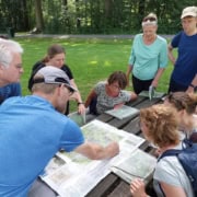 Kaart en kompas navigatie workshop_19 Een groep avonturiers opvallend zich rond een picknicktafel in een park in Utrecht voor een workshop kaart en kompasnavigatie. Enthousiast besproken ze de route terwijl iemand aanduidingen op de kaart maakt. Omringd door groen, klaar om het avontuur tegemoet te gaan.