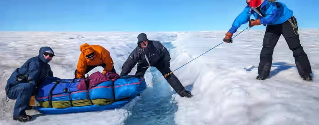 Omslag naar echte ijsberen in de Arctische omgeving, met teamleden die een persoon uit het ijs trekken.