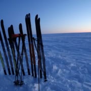 greenland24 Skibescherming en ski's op een sneeuwveld tijdens zonsondergang in de Arctische omgeving.