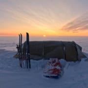 Schotel onder een polarzon met hoogteverschil, skispullen klaar voor een avontuur in de sneeuw, bij zonsondergang in de Arctic.