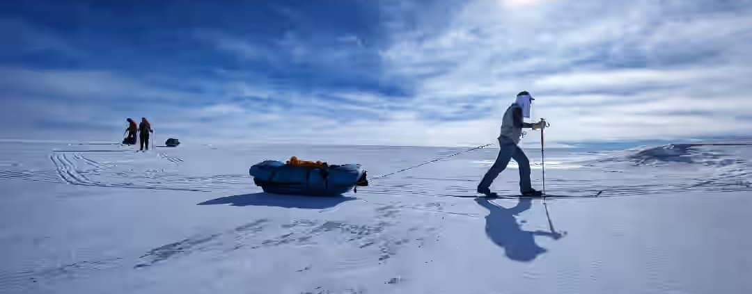 Greenland Expedition Day 23: Sun, Ice, and Crevasses 1 Sneeuwscooter explorers die door een witte, bevroren landschap trekken under een heldere hemel.