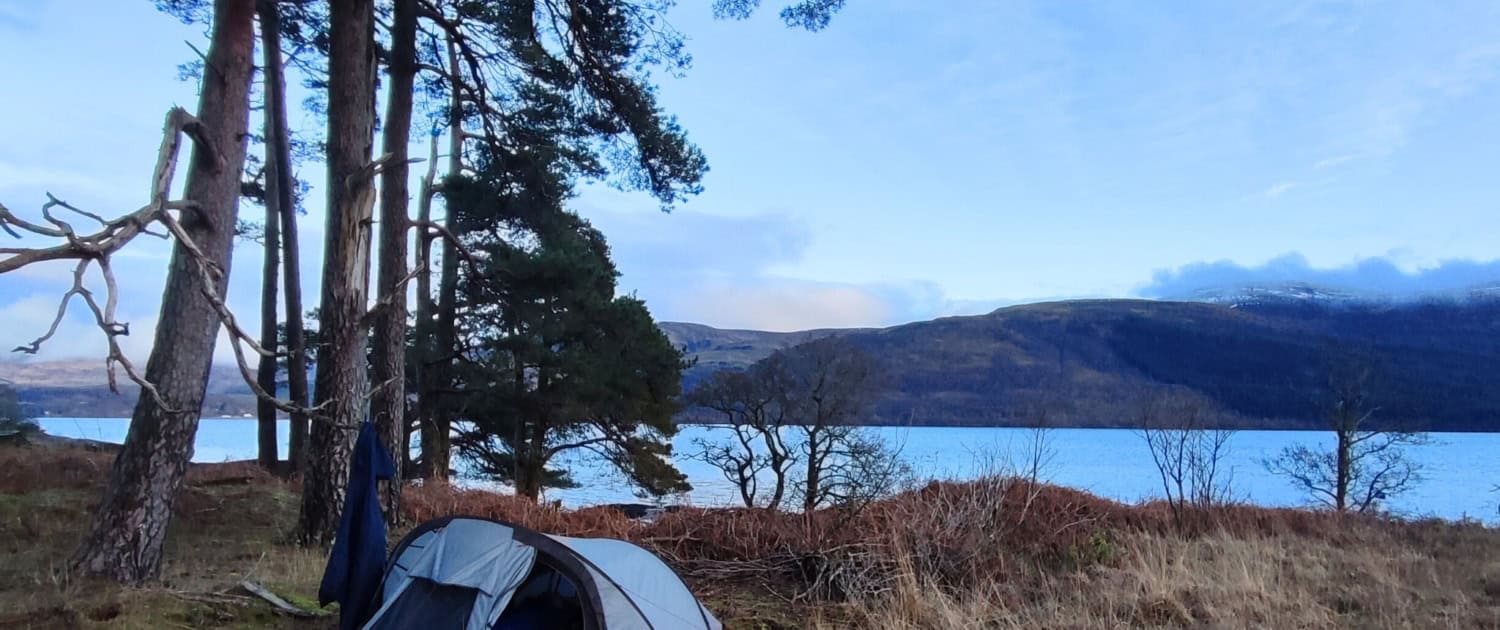 Kampeerplaats aan een meer in een bosrijke omgeving, perfect voor outdoor avonturen en kamperen.