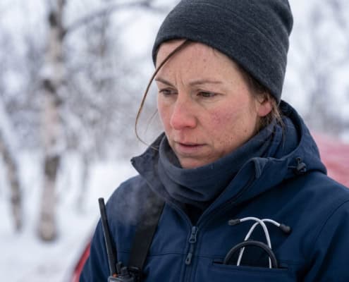 High-resolution photo of a woman in winter clothing in a snowy forest, with a red tent in the background.