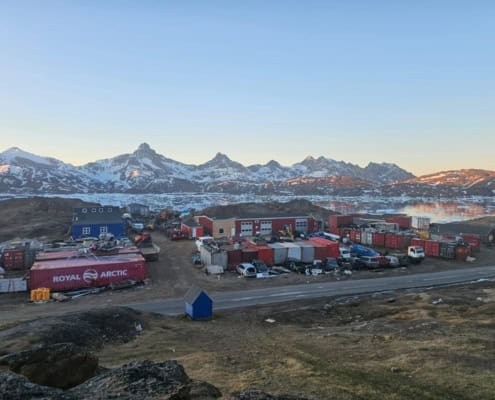 Uitzicht op arctisch landschap met containers en bergen in de achtergrond.