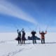 Group of people with skis on the snow in Greenland under a blue sky.