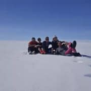 Groep mensen geniet van sneeuwscooterrit in de Arctische sneeuw onder een heldere blauwe hemel.