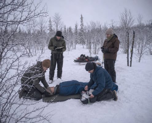 Rescuers provide first aid to a person in the snow during an outdoor workshop.