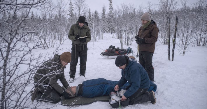 Rescuers provide first aid to a person in the snow during an outdoor workshop.