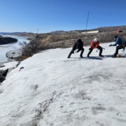 Three people pulling pulks across the Greenland ice plain during an expedition.