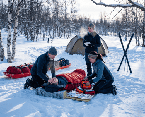 Swimmer being resuscitated by rescuers in a snowy environment.