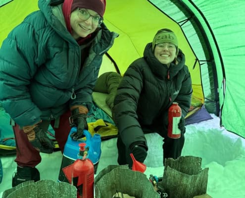 Sneeuwscooter workshop in de sneeuw met twee enthousiaste deelnemers in een tent.