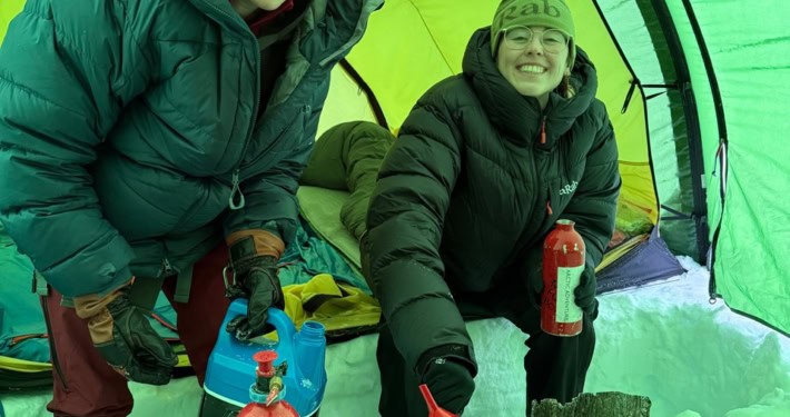 Sneeuwscooter workshop in de sneeuw met twee enthousiaste deelnemers in een tent.