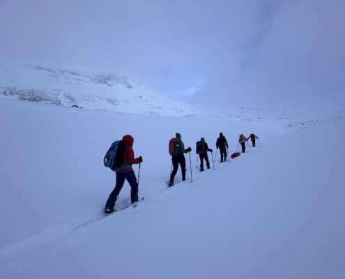 Winterwandelaars in sneeuwlandschap met bergachtergrond.