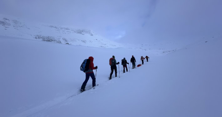 Winterwandelaars in sneeuwlandschap met bergachtergrond.